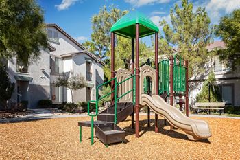 A playground with a green slide and a brown and green play structure.